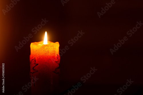 Solitary orange candle in dark