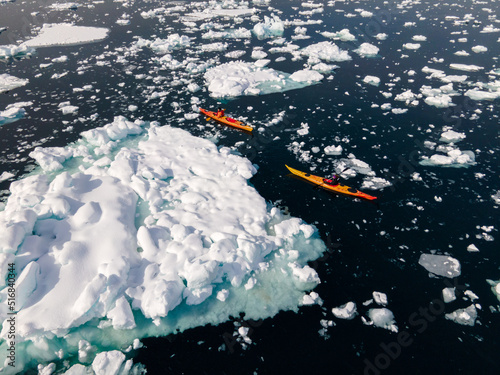 kayak next to a gigantic iceberg in ilulissat greenland outdoor sports kayaking along frozen icebergs in open sea water photo