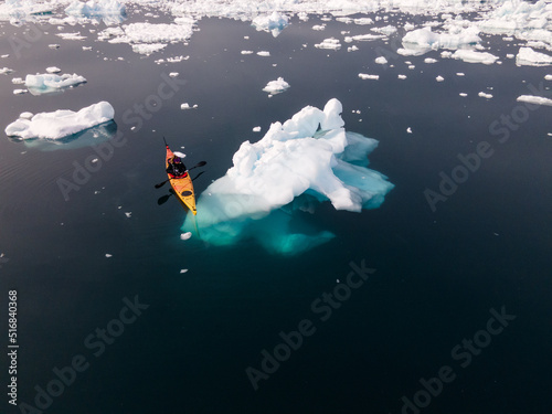 kayak next to a gigantic iceberg in ilulissat greenland outdoor sports kayaking along frozen icebergs in open sea water photo