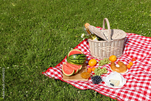 Fototapeta Naklejka Na Ścianę i Meble -  Picnic blanket with delicious food and wine outdoors on summer day, space for text