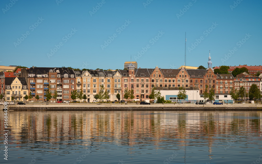 Blick auf eine Häuserfront der dänischen Stadt Aarhus vom Hafen aus gesehen vor blauem Himmel