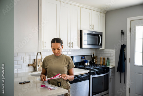 Fotografi U.S. Army female soldier opening her mail in her kitchen
