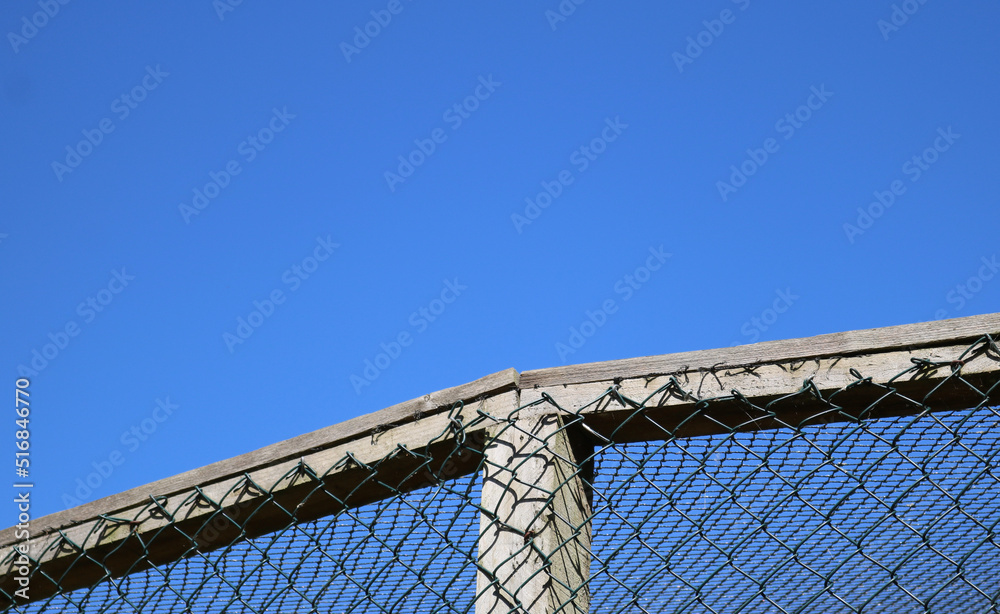 Fototapeta premium Enclosure background showing netted cage against deep blue sky with copy space