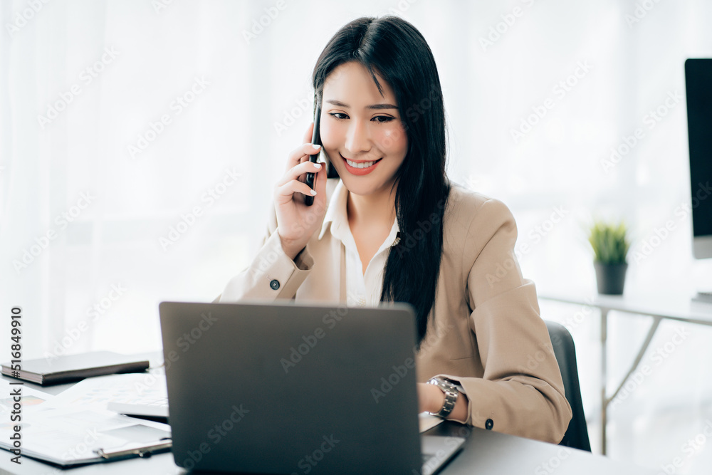 Young asian businesswoman beautiful charming smiling and talking on the mobile phone in the office