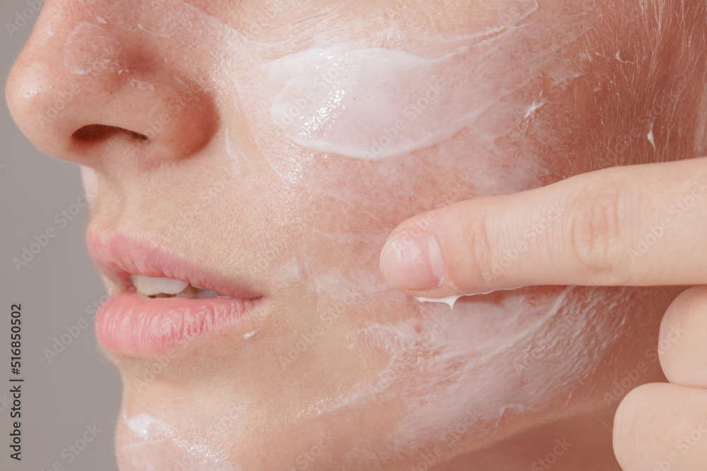 Fototapeta premium young woman applying moisturizer