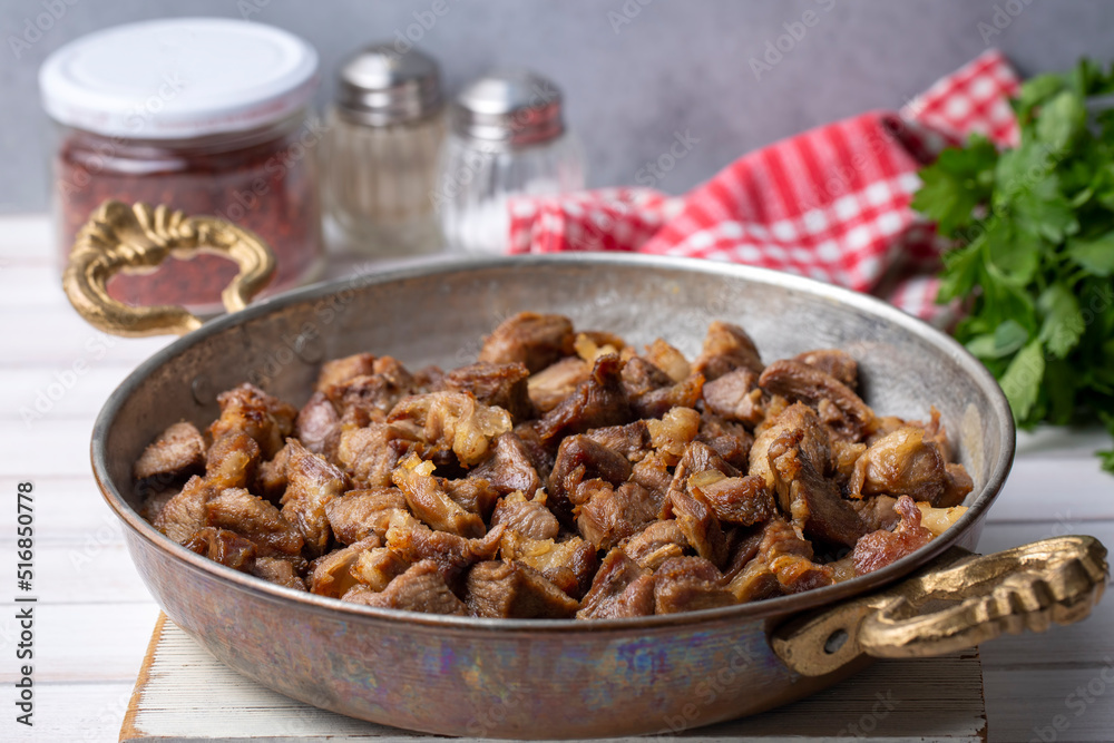Muslims Traditional Sacrifice holiday food lamb, Turkish roasted meat in copper pot on table top. Turkish Kavurma. (Turkish name; Kurban kavurma) Muslims Traditional Sacrifice holiday food lamb, Turkish roasted meat in copper pot on table top. Turkish Kavurma. (Turkish name; Kurban kavurma)