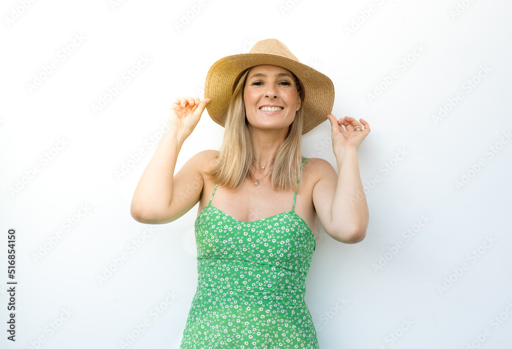 Beautiful attractive stylish woman in green dress and straw hat posing on white wall isolated happy smiling face expression. Summertime concept. Beautiful attractive stylish woman in green dress and straw hat posing on white wall isolated happy smiling face expression. Summertime concept.