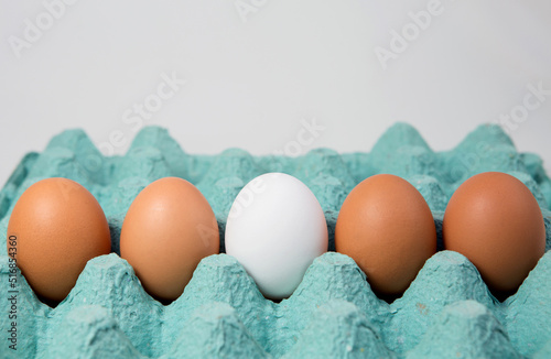 Single white egg among brown eggs