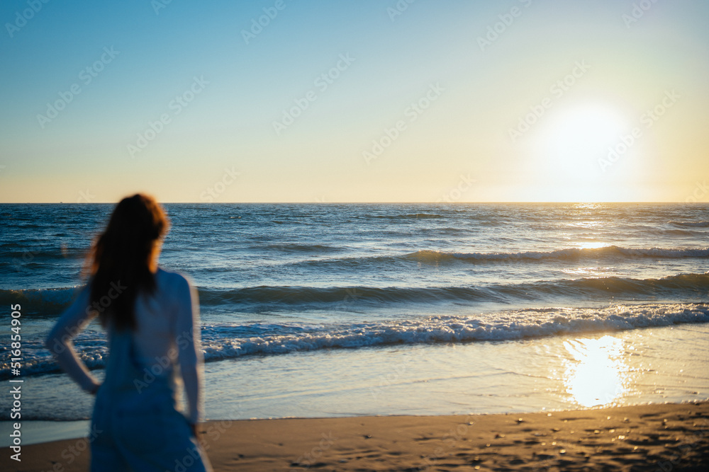 unfocused woman watches the sunset over the sea