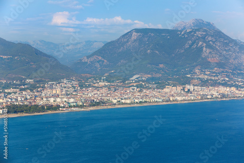 Panoramic view of the coast of Alanya, Turkey. Residential houses, hotels against the backdrop of mountains. Blue water and golden beaches in sunlight. Aerial view