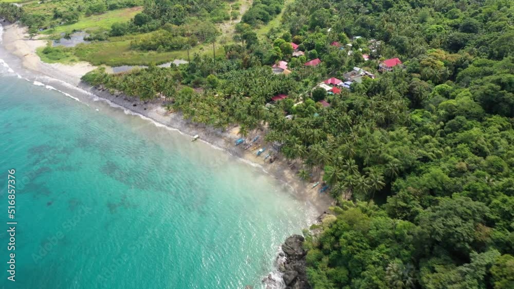 Birds eye view of calm and clear ocean and white sandy beach, along a coastline with tourist villas and lush green vegetation in the Philippines. Birds eye view of calm and clear ocean and white sandy beach, along a coastline with tourist villas and lush green vegetation in the Philippines.