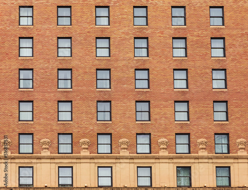 Many windows in row on facade of urban apartment building. Brick building.