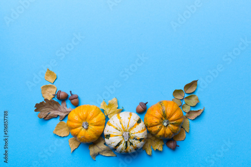 Autumn composition Pumpkins with fall leaves over coloredbackground. Top view with copy space photo