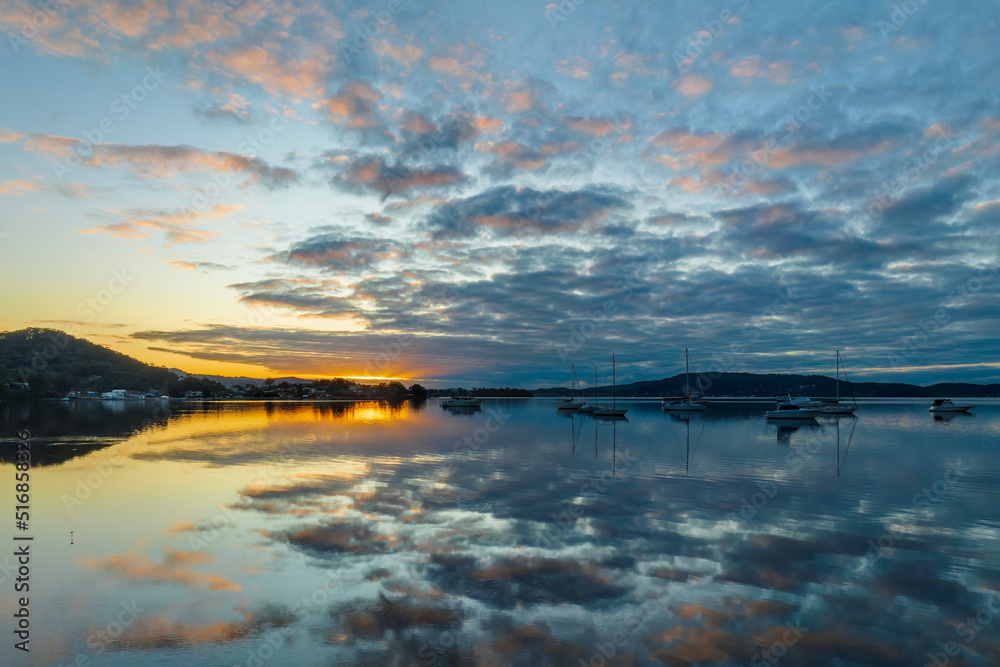 Aerial sunrise waterscape with boats, reflections and cloud filled sky