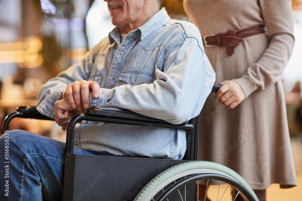 Obraz premium Close-up of female volunteer in dress pushing aged man in wheelchair while working with handicapped man in nursing home
