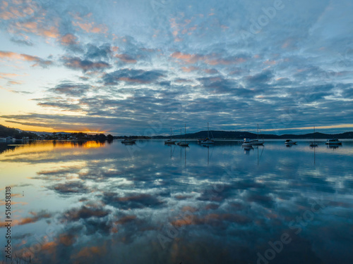 Aerial sunrise waterscape with boats  reflections and cloud filled sky