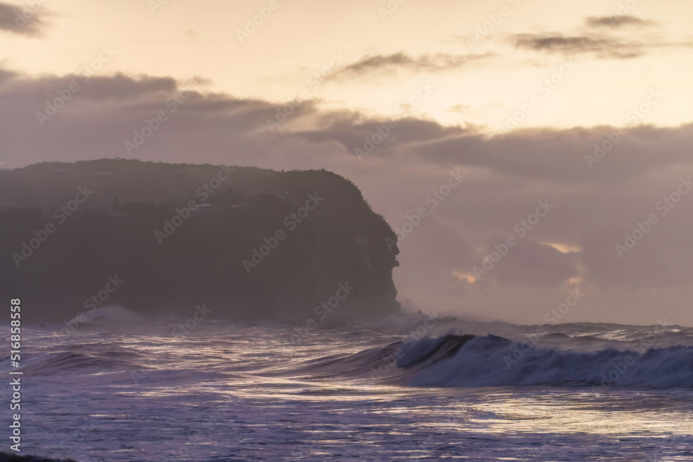 Sunrise at the seaside with big waves and clouds