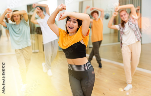 Group of positive teenagers dancing modern dance in ballroom.