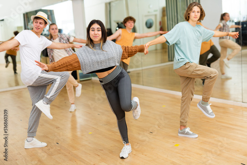 Cheerful hispanic teenage girl learning to dance vigorous jive in pair with boy in choreography class.