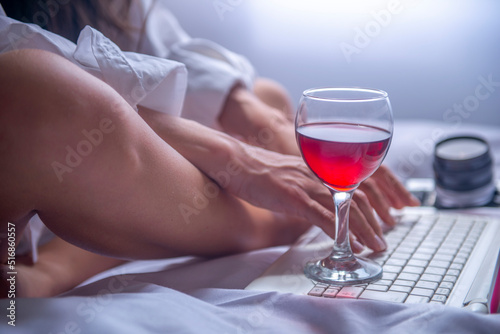 relaxed businesswoman working on her computer with her wine