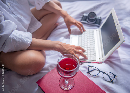 relaxed businesswoman working on her computer with her wine