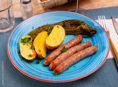 Fried homemade sausages with baked potatoes and baked pepper at plate
