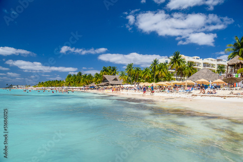 People swimming near white sand beach with umbrellas, bungalow bar and cocos palms, turquoise caribbean sea, Isla Mujeres island, Caribbean Sea, Cancun, Yucatan, Mexico © Eagle2308