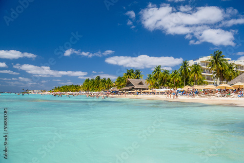 People swimming near white sand beach with umbrellas, bungalow bar and cocos palms, turquoise caribbean sea, Isla Mujeres island, Caribbean Sea, Cancun, Yucatan, Mexico