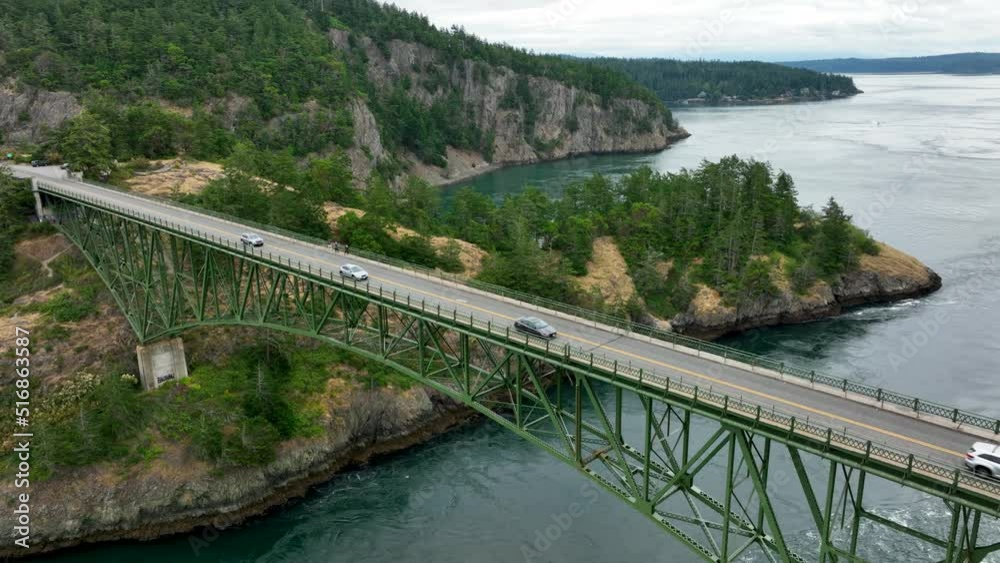Wide static aerial view of cars commuting over the Deception Pass bridge. Wide static aerial view of cars commuting over the Deception Pass bridge.