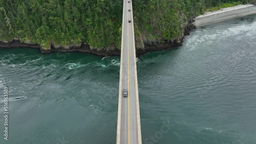 Top down drone shot tracking a car across a bridge over the ocean. photo