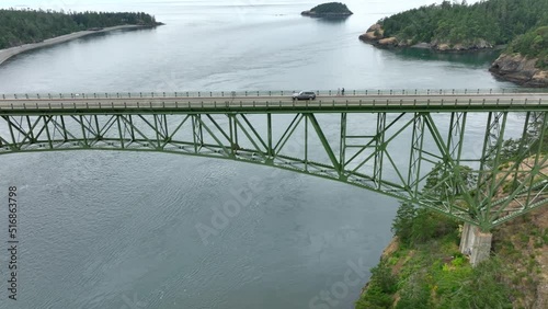 Single car driving across the green steel bridge at Deception Pass State Park. photo