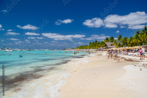 People swimming near white sand beach with umbrellas, bungalow bar and cocos palms, turquoise caribbean sea, Isla Mujeres island, Caribbean Sea, Cancun, Yucatan, Mexico