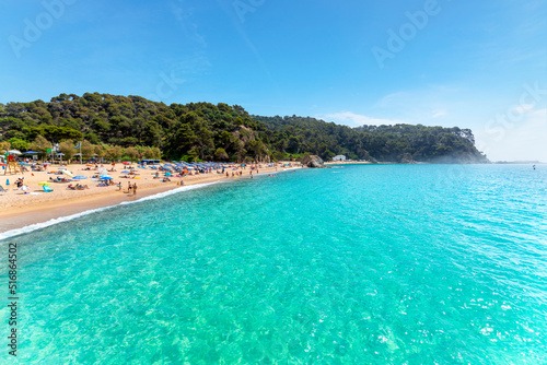 View from the clear turquoise sea as the fog breaks at morning along the Cala Santa Cristina sandy beach on the Costa Brava coast in Lloret de Mar, Spain. photo
