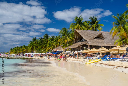 People sunbathing on the white sand beach with umbrellas, bungalow bar and cocos palms, turquoise caribbean sea, Isla Mujeres island, Caribbean Sea, Cancun, Yucatan, Mexico