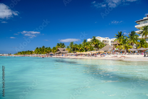 People sunbathing on the white sand beach with umbrellas, bungalow bar and cocos palms, turquoise caribbean sea, Isla Mujeres island, Caribbean Sea, Cancun, Yucatan, Mexico