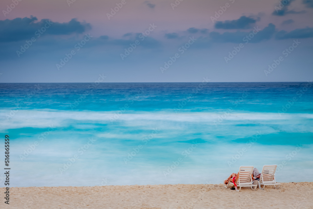 Couple relaxing at sunset on the caribbean beach of Cancun, Mexico