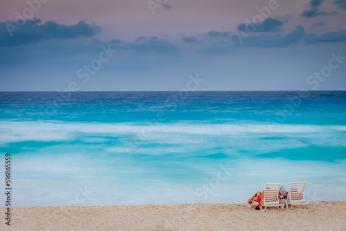 Couple relaxing at sunset on the caribbean beach of Cancun, Mexico