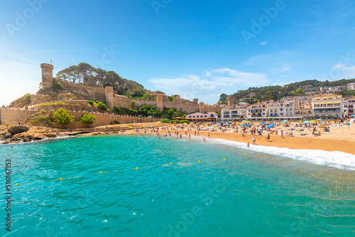 Fototapeta Naklejka Na Ścianę i Meble -  The sandy Playa Grande beach at the seaside Spanish town of Tossa de Mar, Spain, with the historic 12th Century castle above it on the Costa Brava coast.