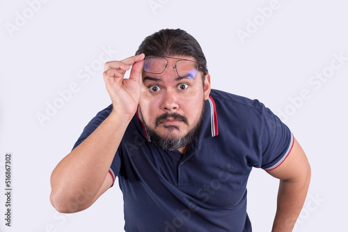 A middle aged man removing glasses and leaning forward in an attempt to focus clearly at something. Wearing the wrong grade and prescription of glasses. Isolated on a white backdrop. photo