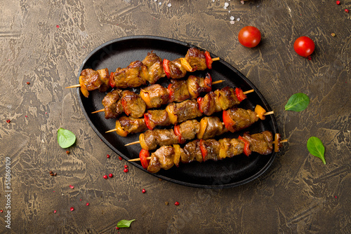 Kebabs of pork with red bell pepper on black plate top view, canapes