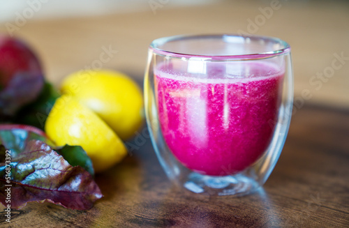 Fresh beetroot smoothie in glass with lemom,apple and beetroot leaves on dark wooden background. photo