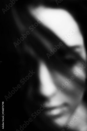 Beauty and fashion concept. Abstract woman portrait silhouette with part face covered with hairs by blowing wind. Black and white image. Defocused, out of focus and blurred image. Black copy-space