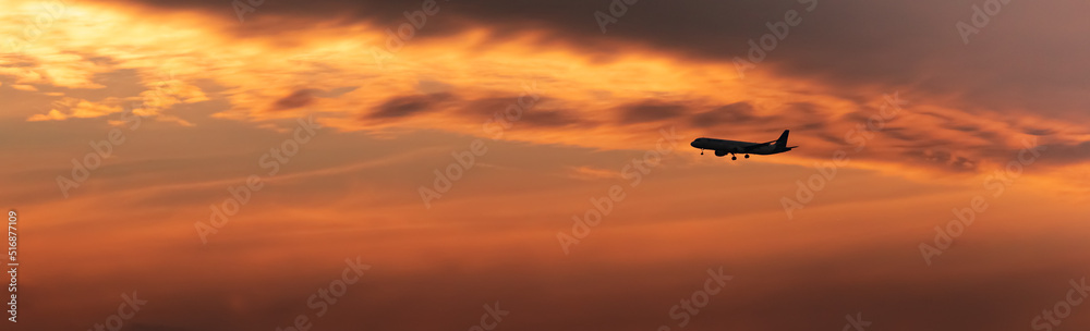 Airplane flying in the sunset and the orange clouds