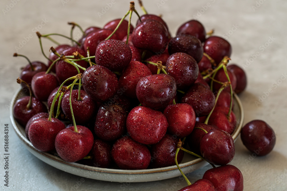 A white ceramic dish with a cherry in the center. Light background. A white ceramic dish with a cherry in the center. Light background.