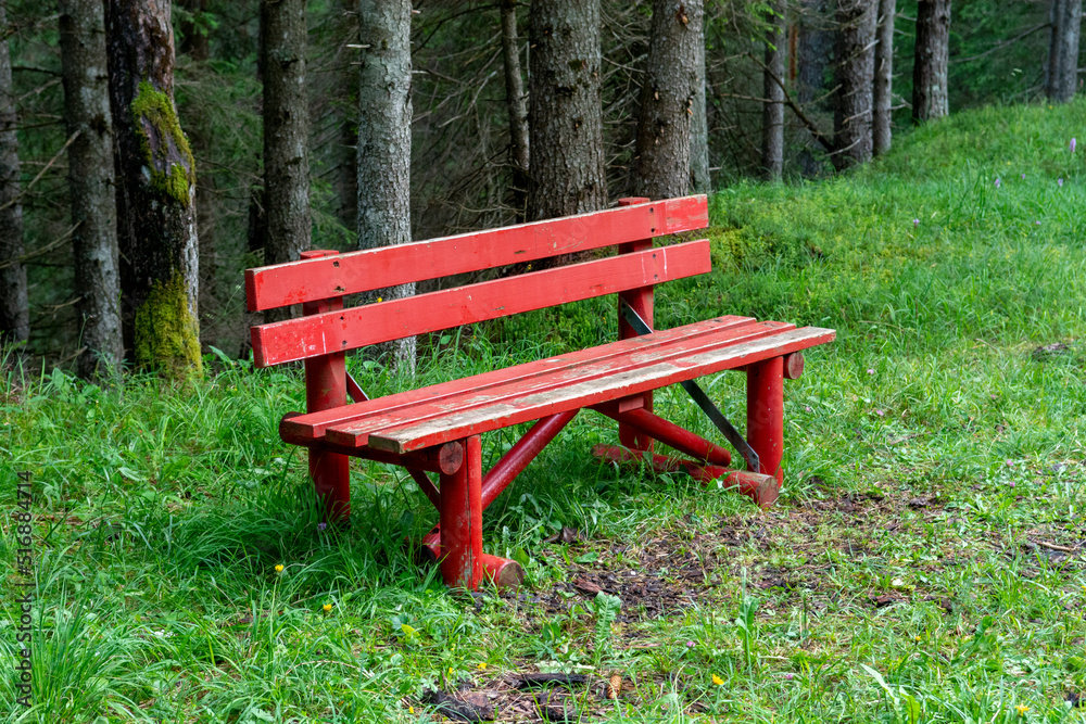 Red wooden bench in the forest. Dolomites. Italy. Red wooden bench in the forest. Dolomites. Italy.