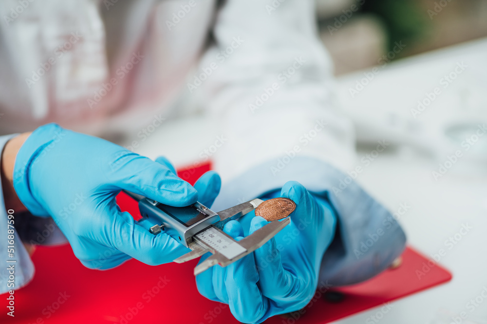 Numismatics expert identifying and documenting coin collection, using caliper