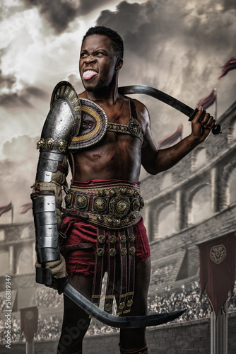 Shot of funny african gladiator holding two swords showing his tongue in arena looking away.