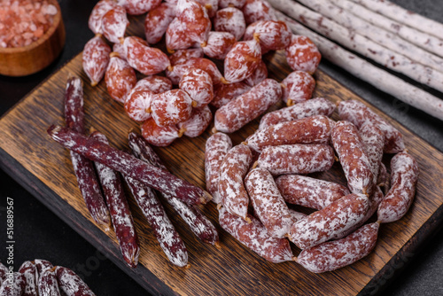 Delicious dry sausage with walnuts on a concrete table. Dry cured fuet sausage on a dark background