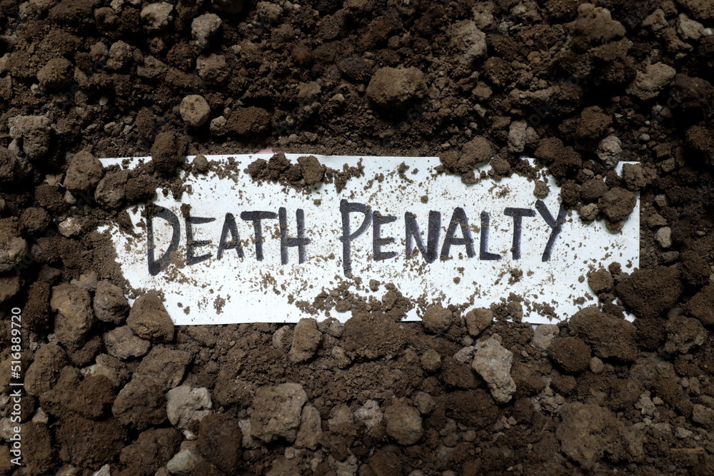Death penalty concept. Written word on paper under soil.