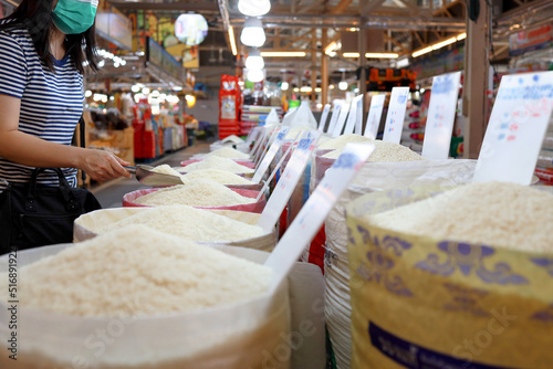 Female consumer buying grains of thai fragrant rice,choosing raw white rice,asian woman shopping in the market,purchasing or hoarding for dry food,rice prices problem,concept of nutrition,consumption